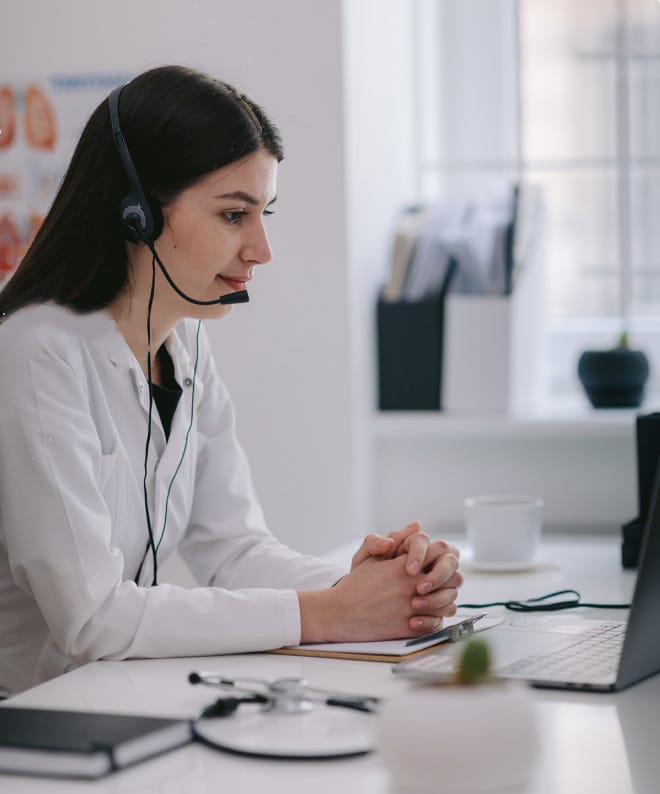 Woman doctor on the phone, looking at computer smiling