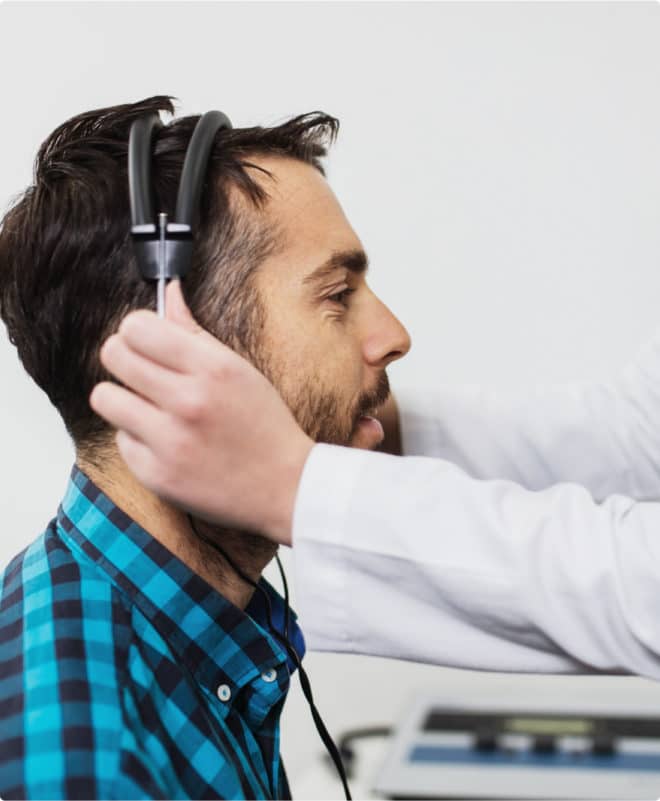 Doctor placing headphones on a male patient during testing