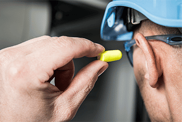 A construction worker protects his hearing by putting in earplugs on a Michigan job site.