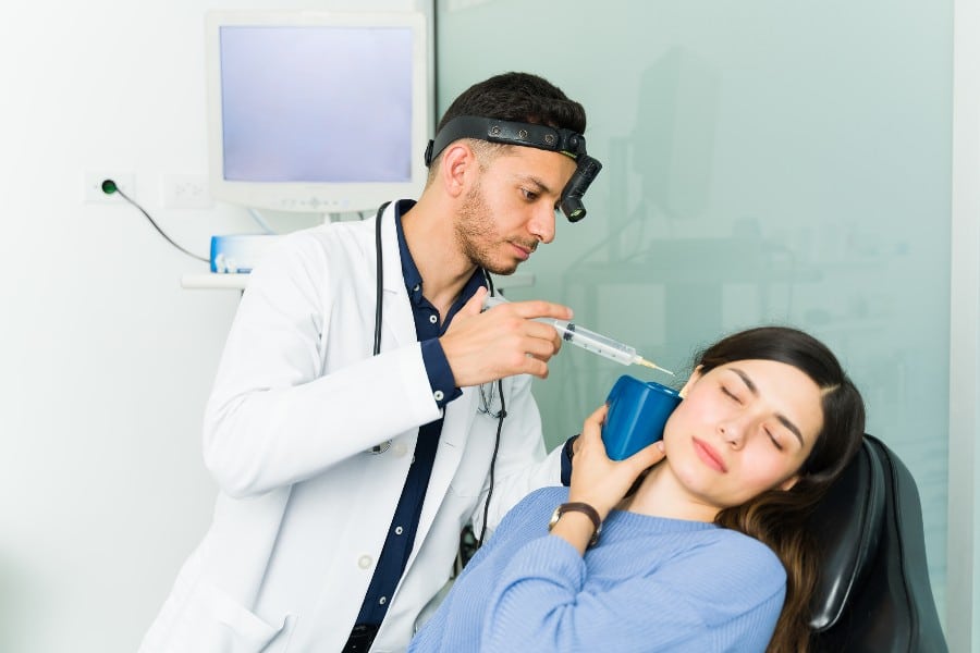 A hearing specialist from Estes Audiology performs a routine ear cleaning on a patient from Texas.